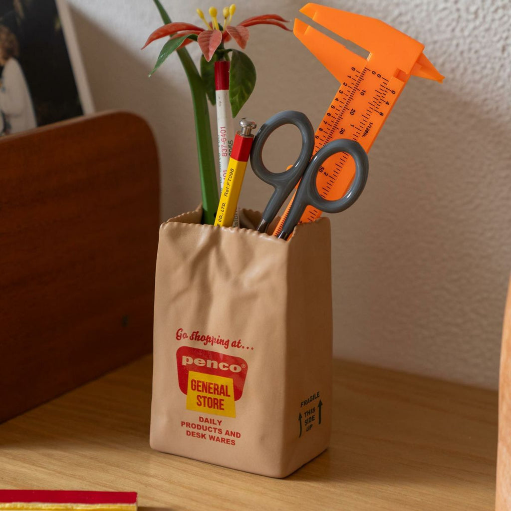 Hightide Penco Brown Bag Stand used as a pen holder on a desk.

