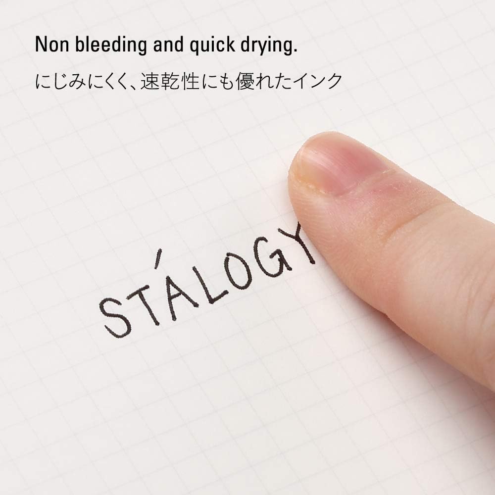 A close-up showing the pen’s tip as it writes the word 'STALOGY', demonstrating the non-bleeding and quick-drying properties of the ink.
