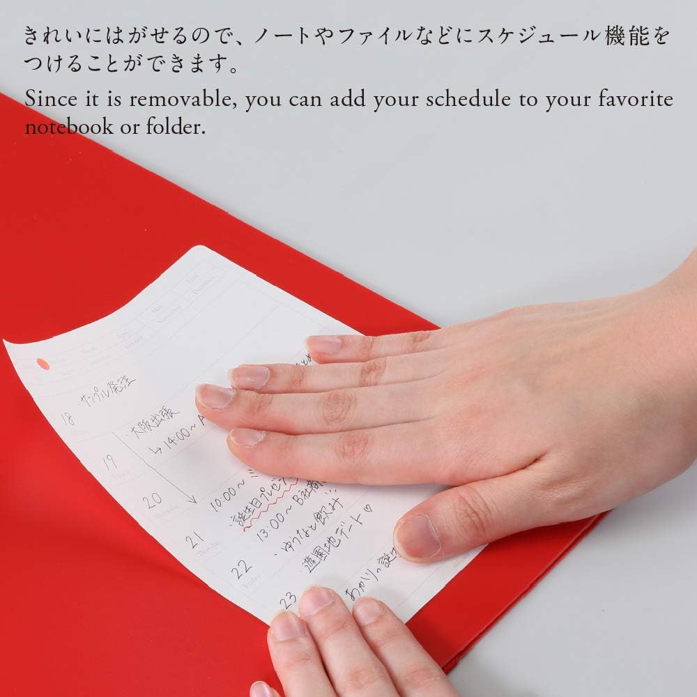 Close-up of a hand peeling a small, adhesive calendar sticker from a diary.