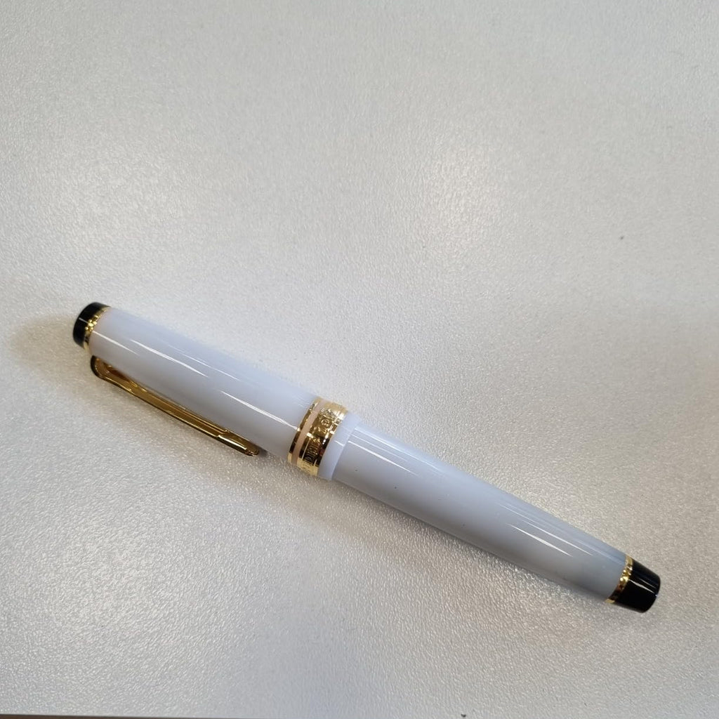 White pen with gold accents on a light gray surface