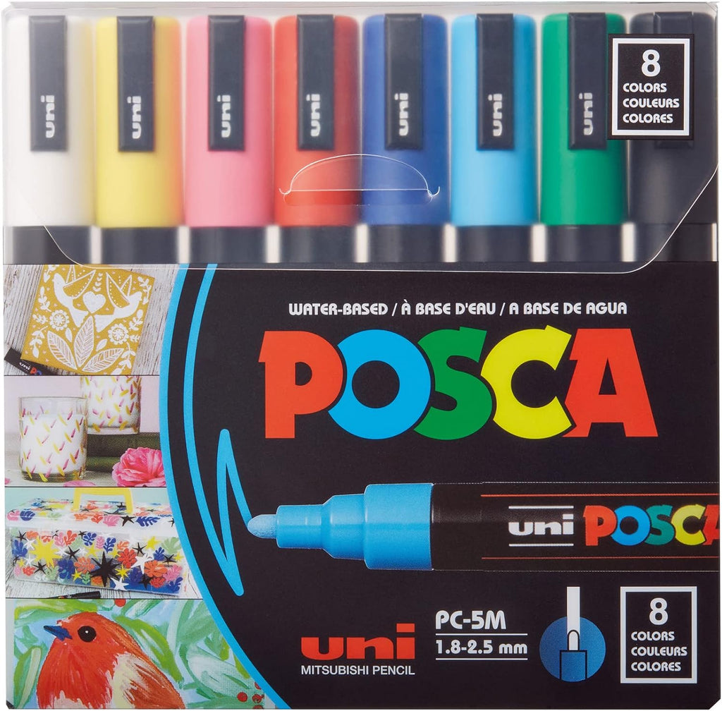 Uni Posca PC5M8C medium point markers set of 8 arranged neatly on a drawing desk with various artworks