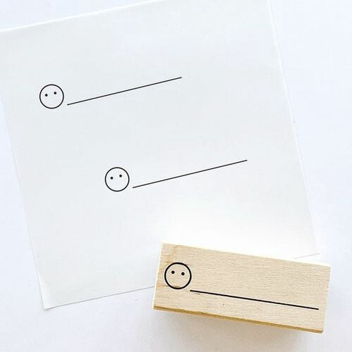 Wooden stamp with a dot face and line design, allowing users to customise expressions. Displayed on white paper, ideal for bullet journaling. Measurements: 50 x 20 x 24mm.
