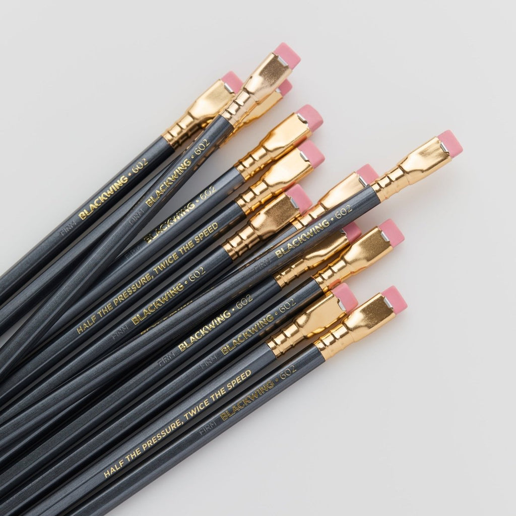 Overhead view of multiple Blackwing 602 pencils fanned out to display gold ferrules and pink erasers.