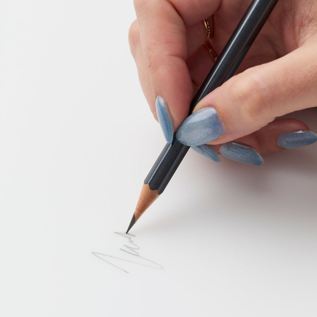 Person sketching with a Blackwing 602 pencil on white paper.