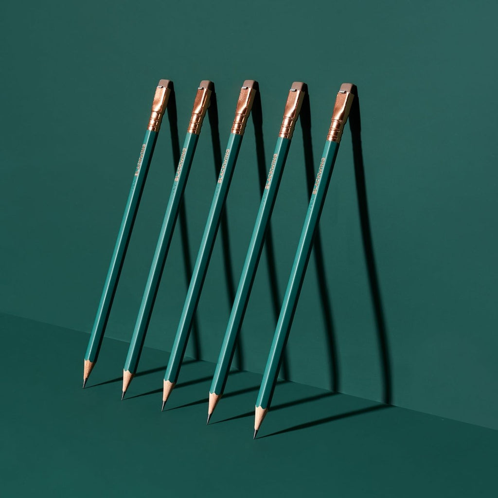 Set of Blackwing Matte Green pencils arranged upright in a standing formation on a dark background.
