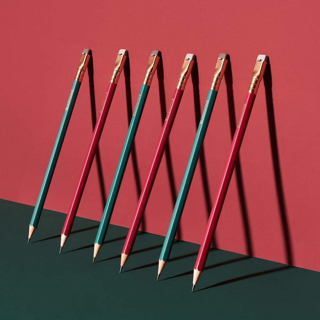 Blackwing Matte Green pencils arranged in a standing formation on a red background.
