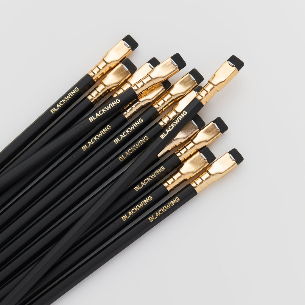 Overhead view of multiple Blackwing Matte pencils fanned out to show gold ferrules and black erasers.