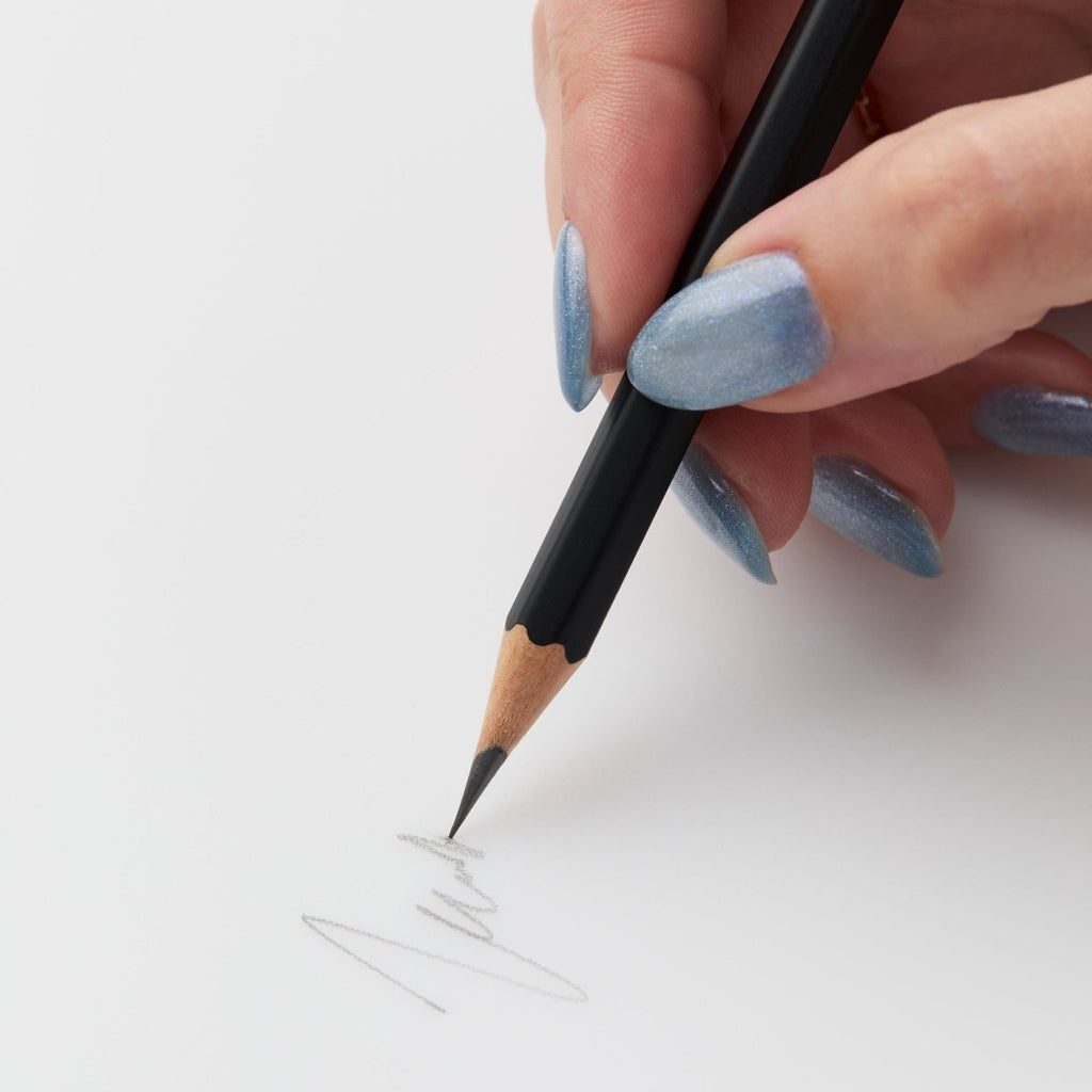 Person sketching with a Blackwing Matte pencil on white paper.
