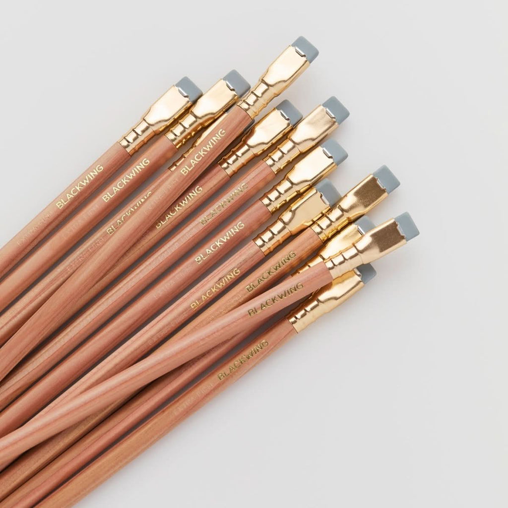 Overhead view of multiple Blackwing Natural pencils fanned out to show ferrules and erasers.