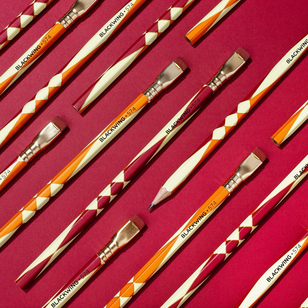 Arrangement of Blackwing Volume 574 pencils on a red background, showcasing the unique design.
