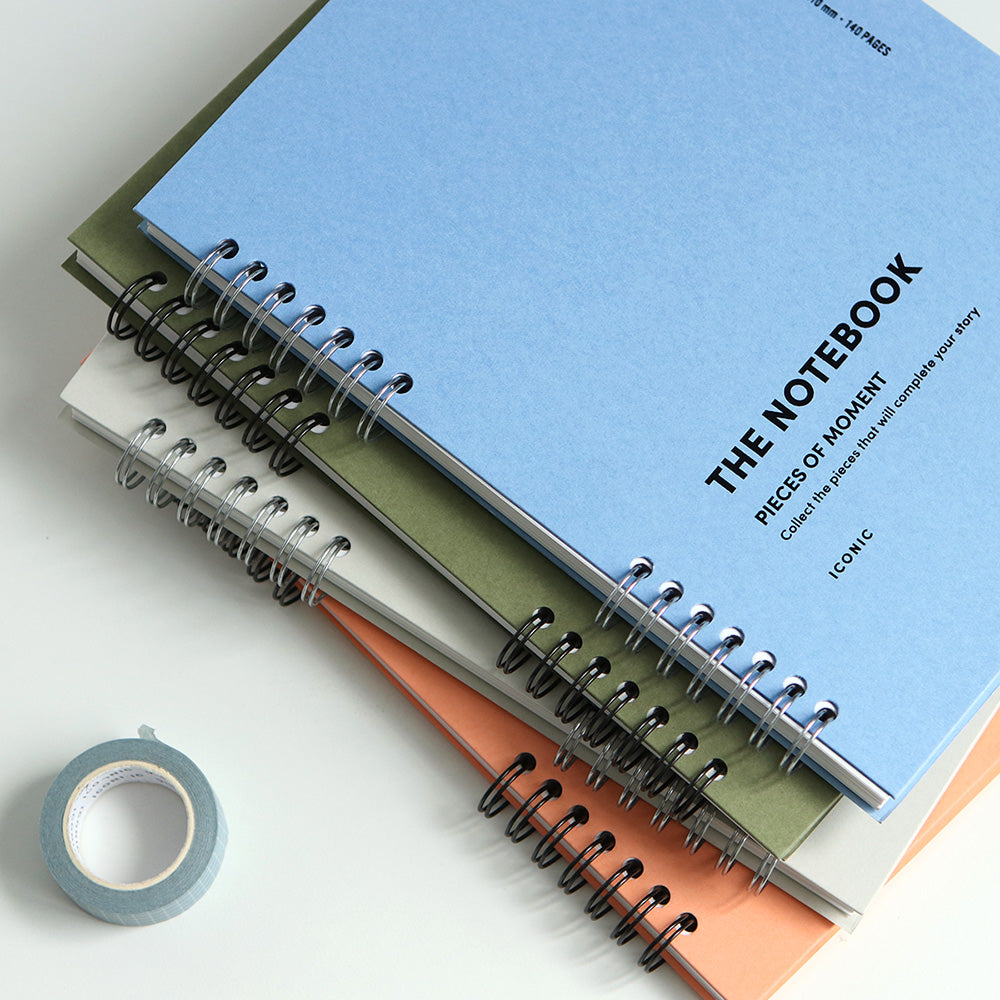 The Iconic Compact A5 Lined Notebook in Light Grey, Orange Coral, and Placid Blue, showing off the range of available colours.