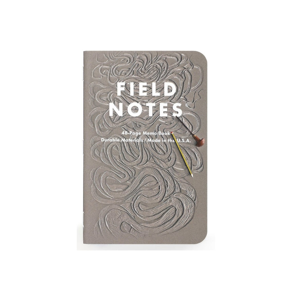 Front cover of Field Notes memo book in grey with engraved river-like textures and paintbrush illustration.