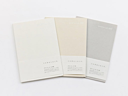Set of three Graphilo A5 notebooks in white, ivory, and grey, displayed with original paper sleeves.