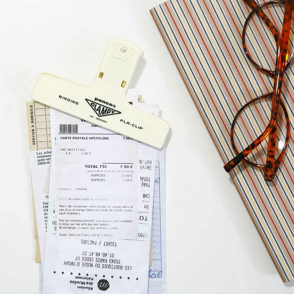 The Journal Shop - Cream Hightide Penco Clampy Pla-Clip securing documents beside stationery items on a light workspace.