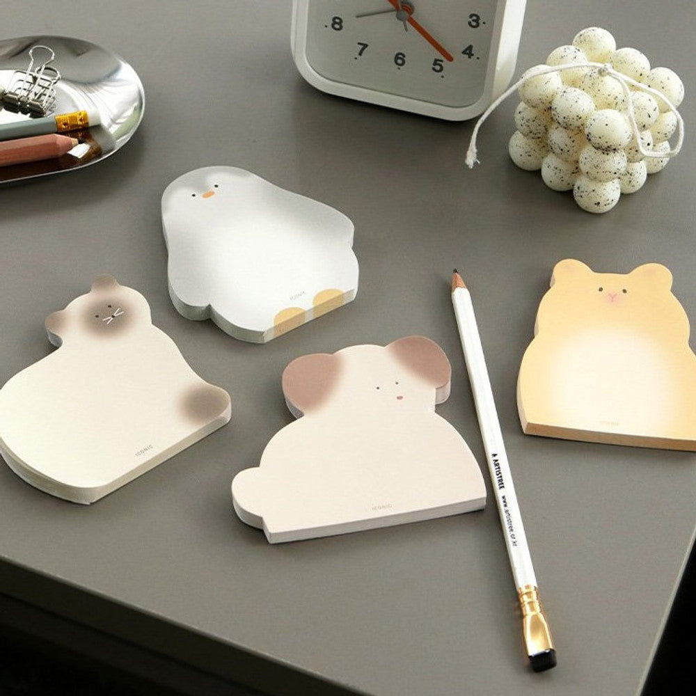 The Journal Shop - A collection of animal-shaped memo pads arranged on a dark grey desk with pens and clips for writing notes.