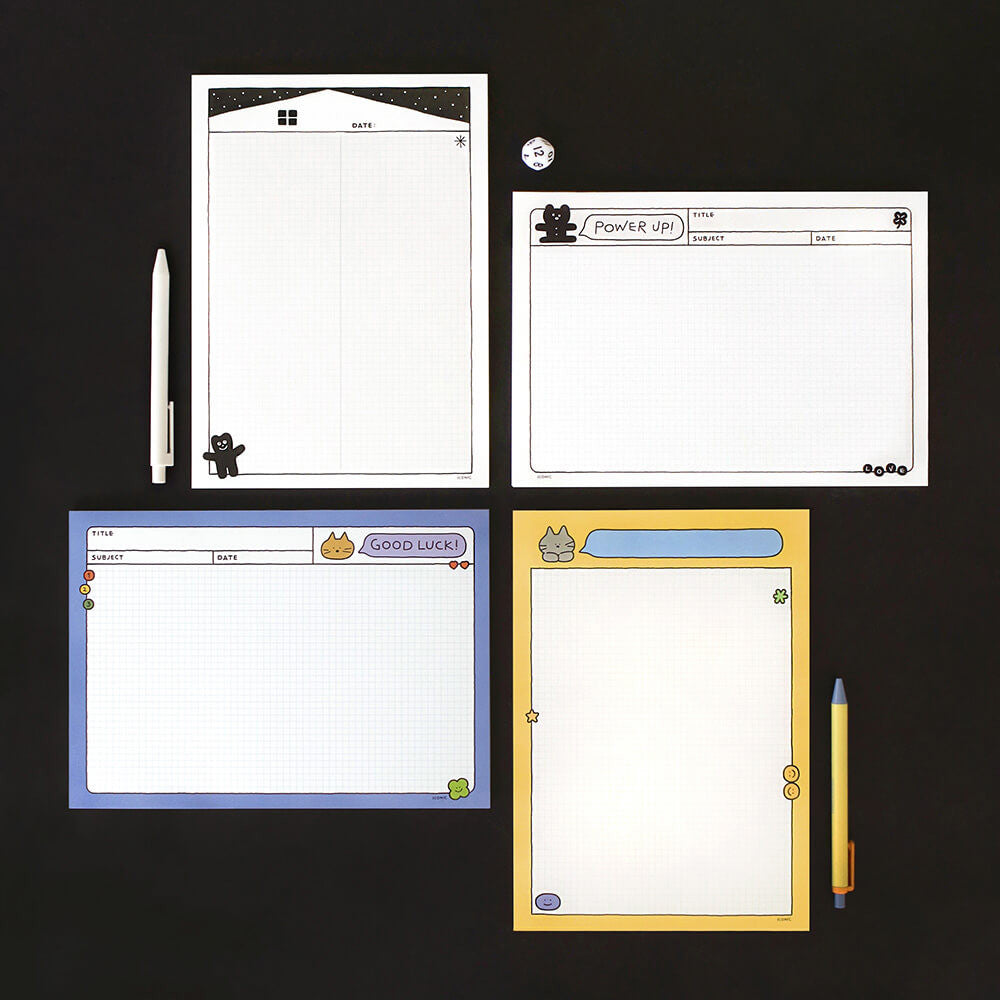 The Journal Shop - Iconic Doodle B5 Grid Notepads in assorted colours displayed flat on desk with pens and stationery.