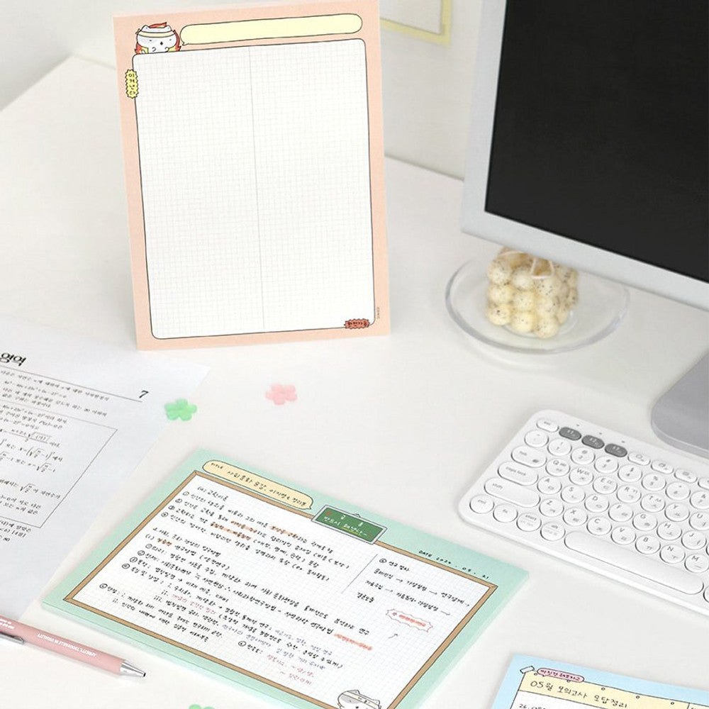 The Journal Shop - Iconic Blah Blah B5 Memo Notepad pastel orange cover version standing upright on desk with stationery beside it.