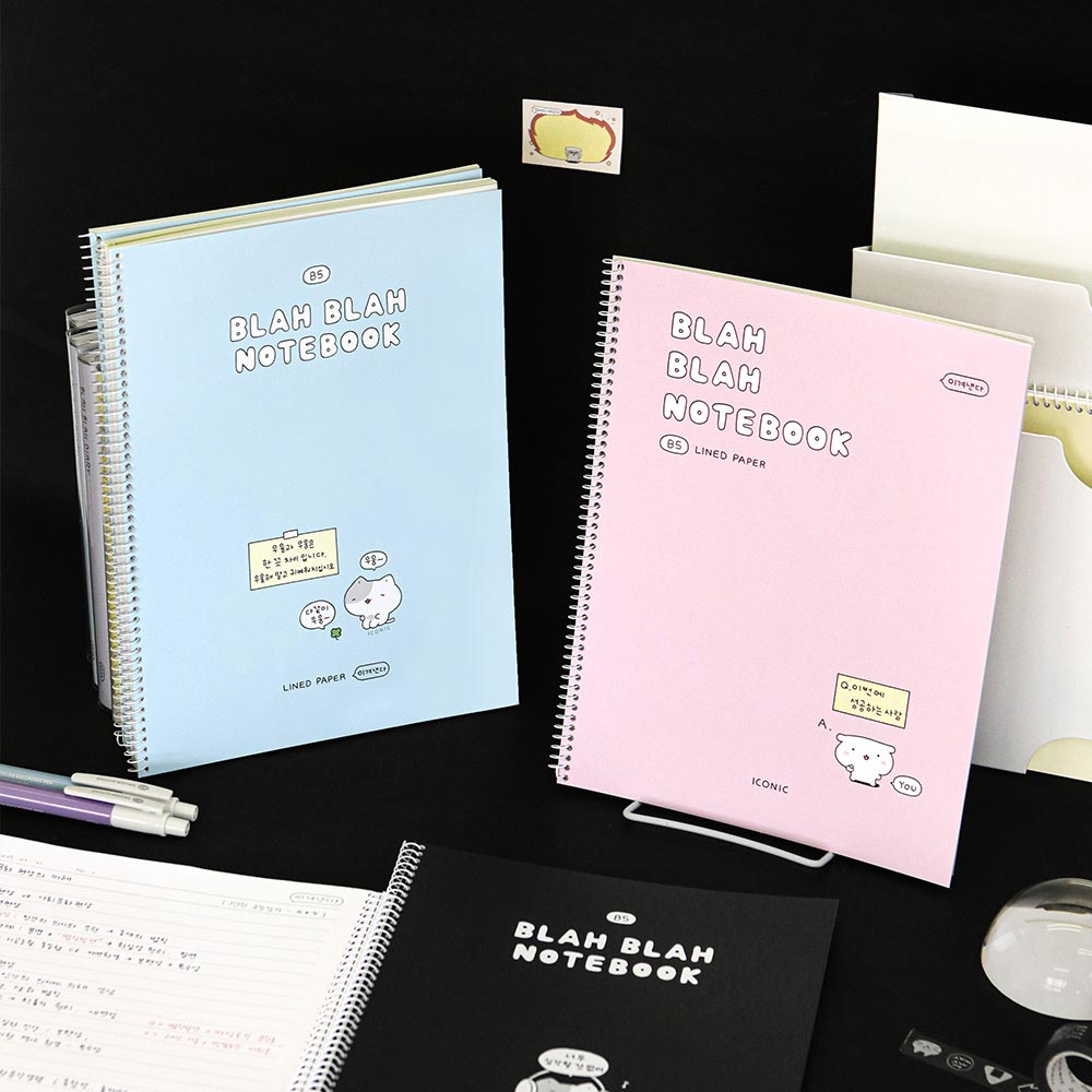 The Journal Shop - Iconic Blah Blah B5 Spiral Lined Notebooks in pastel blue, pink, and black covers displayed with stationery on desk.