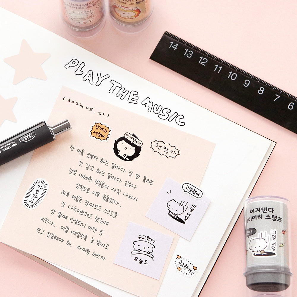 The Journal Shop - A pastel pink surface featuring a pen, notebook, and Iconic Blah Blah Diary Stamps in use on a handwritten note.