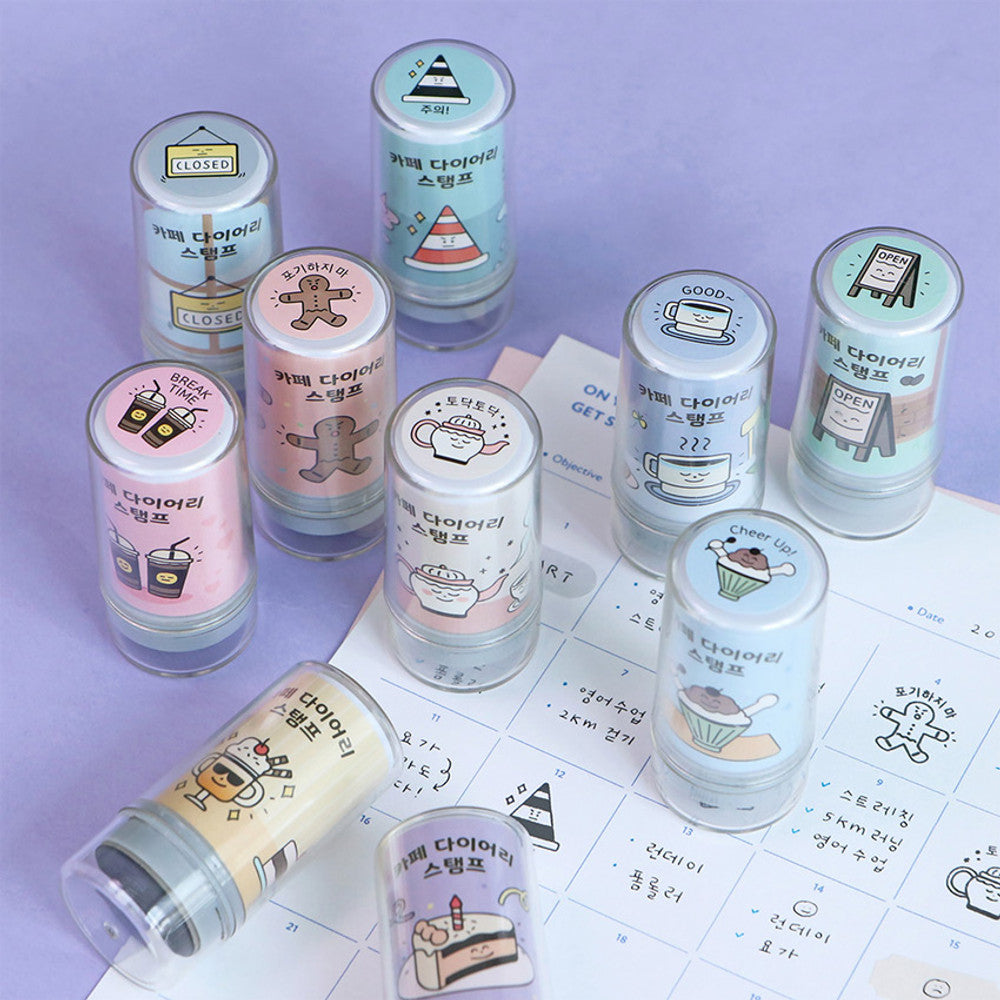The Journal Shop - Assorted café-themed self-inking stamps in pastel tones arranged on a purple background.