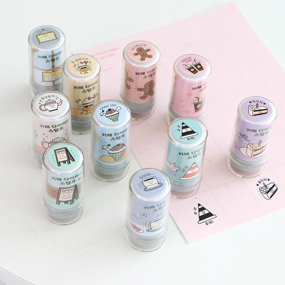 The Journal Shop - Collection of Iconic Café Self-Inking Diary Stamps in assorted pastel colours displayed on pink and white backgrounds.