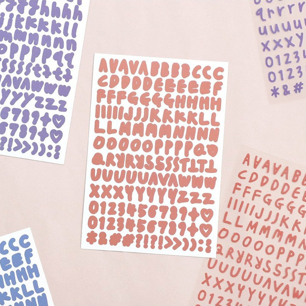 The Journal Shop - Assorted Calli Alphabet Sticker sheets in pastel blue, purple, and pink displayed on a flat surface.