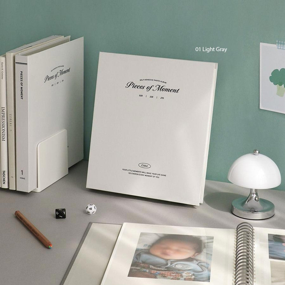The Journal Shop - Iconic Collect Self-Adhesive Photo Album in light grey cover on desk with printed photos and stickers for journaling.