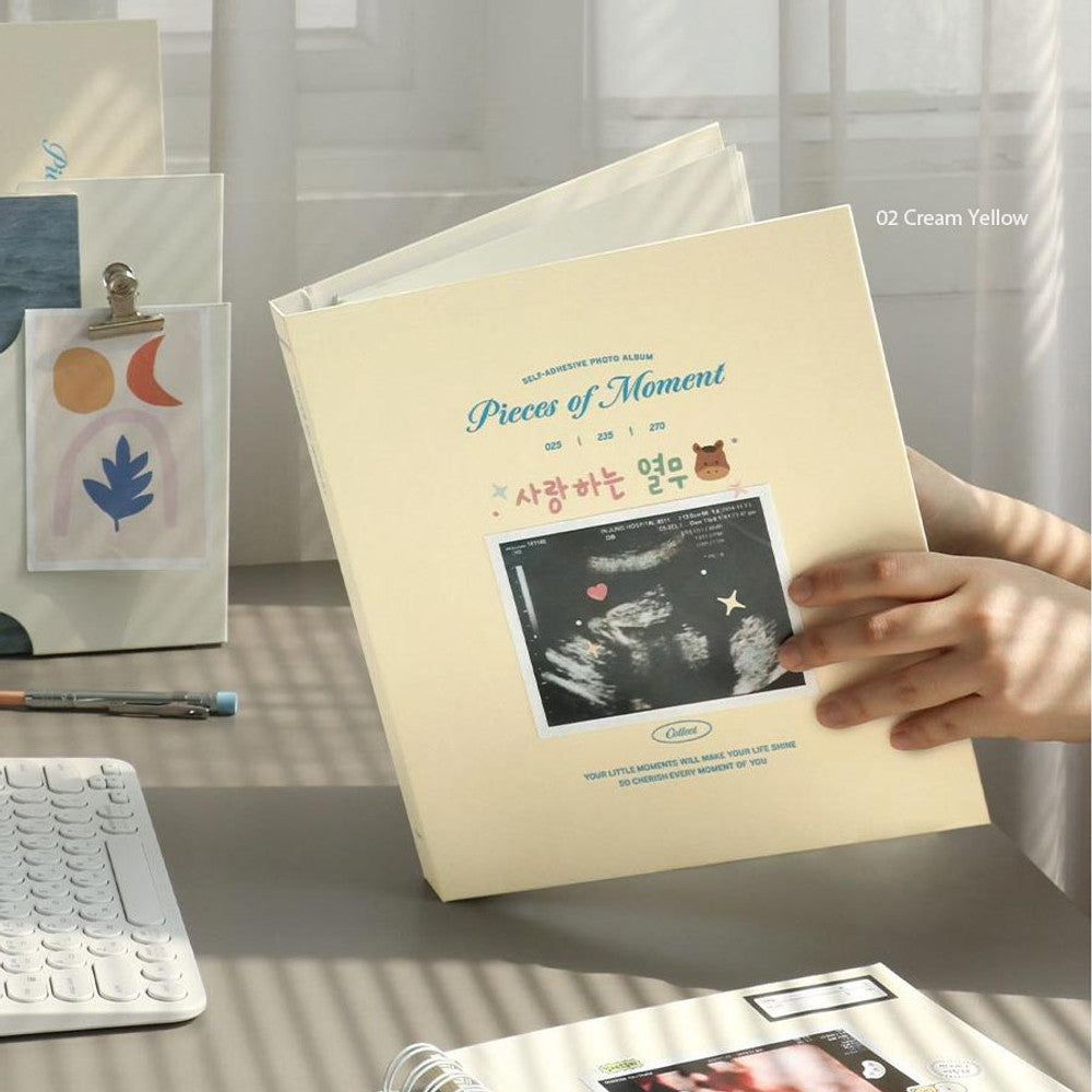 The Journal Shop - Iconic Collect Self-Adhesive Photo Album in cream yellow cover shown in use with hands placing photo inside.