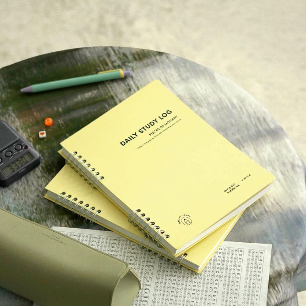 The Journal Shop - Iconic Daily A5 Study Planner dateless notebook in yellow cover shown on desk with pen.