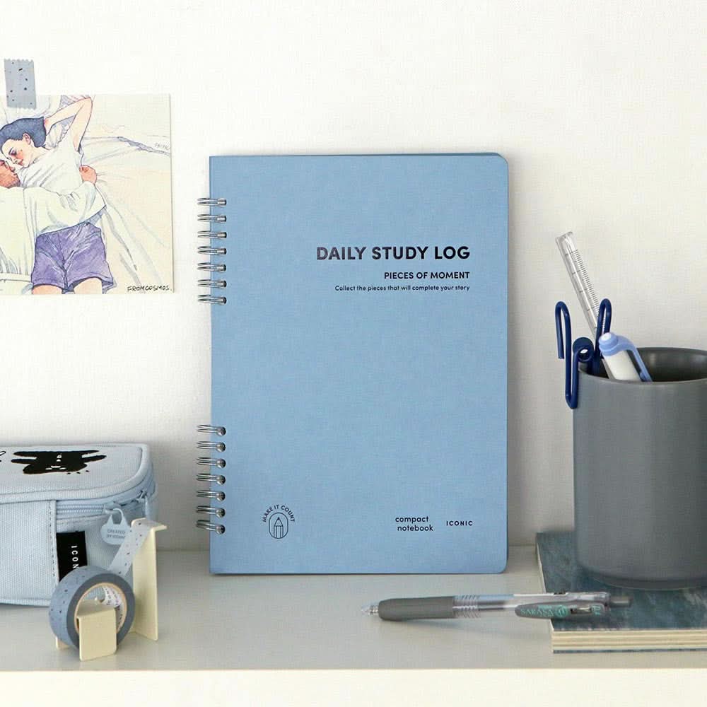 The Journal Shop - Iconic Daily A5 Study Planner dateless productivity notebook in blue cover hanging on wall with clips.