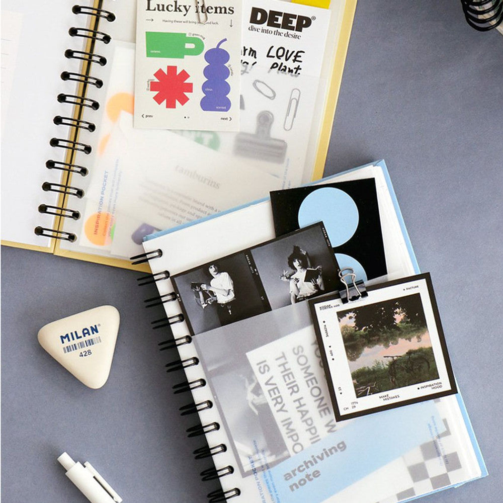 Two open Iconic Daily Archiving Spiral Books filled with photos, stickers, and drawings, showcasing versatile use as a scrapbook or journal.