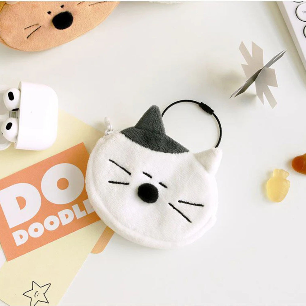 White cat and orange cat-shaped pouches displayed together beside air pods in a white surface.