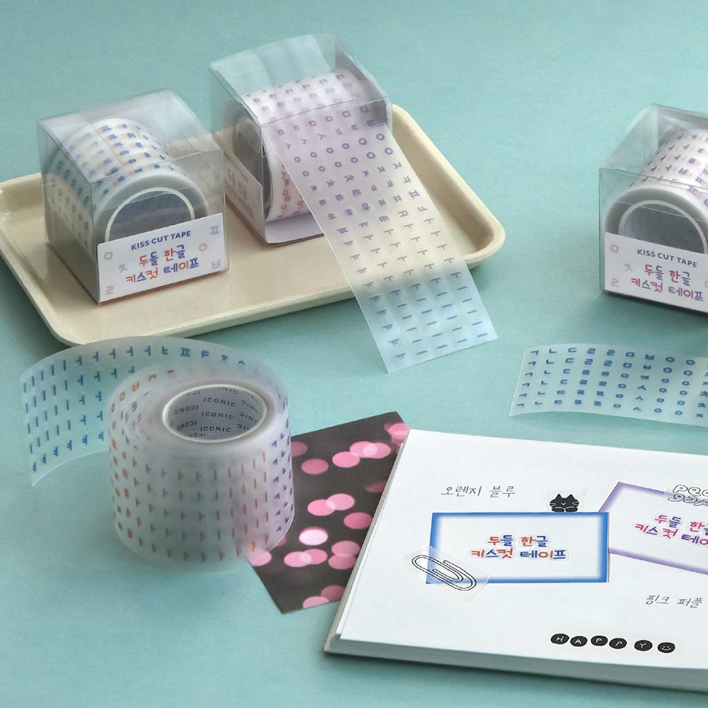 The Journal Shop - Rolls of Iconic Doodle Hangeul Kiss-Cut Tape displayed on a tray with pastel-coloured Korean characters printed on translucent material.