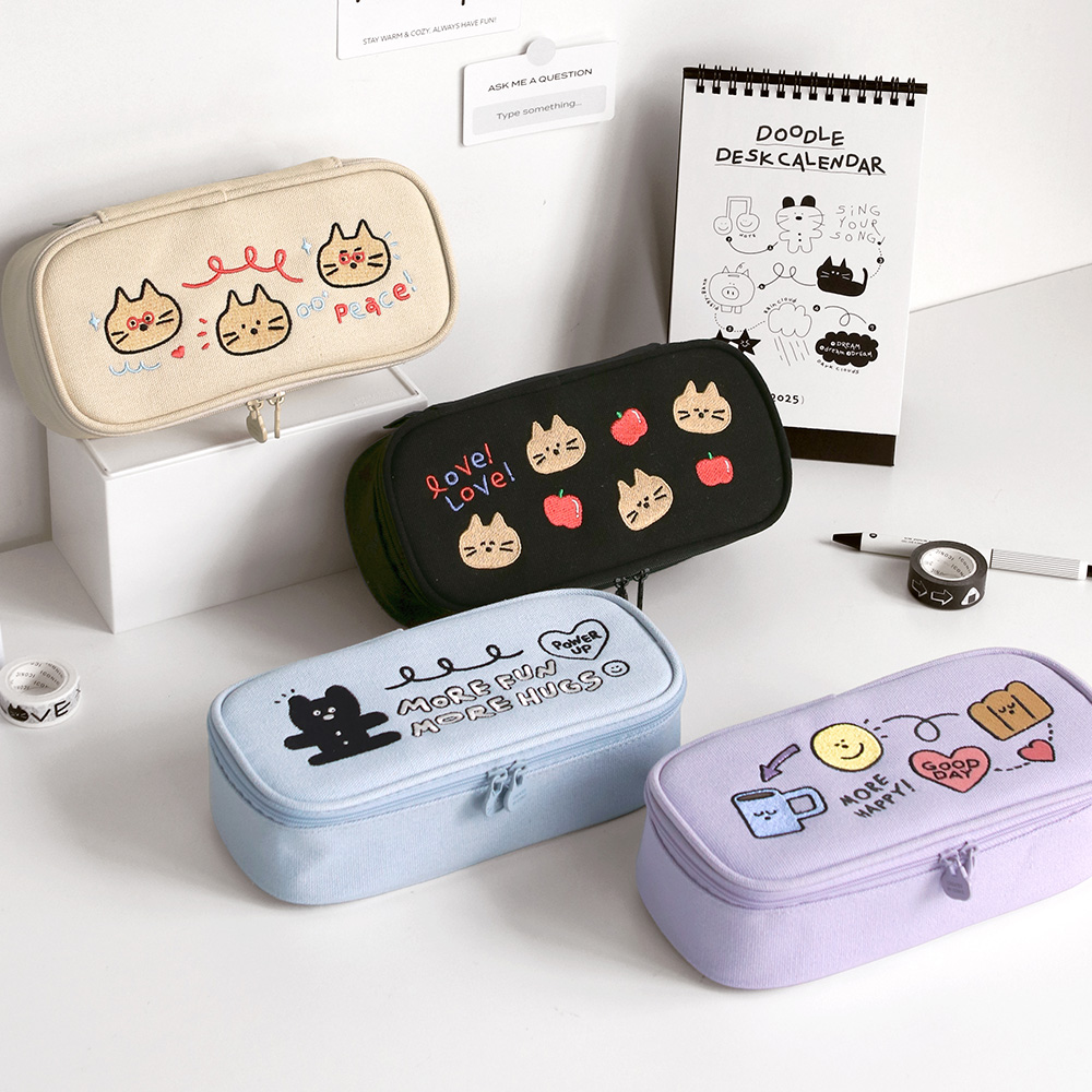 The Journal Shop - Iconic Doodle Large Capacity Pen Pouches in cream, black, blue, and lavender with cute character illustrations on lids.