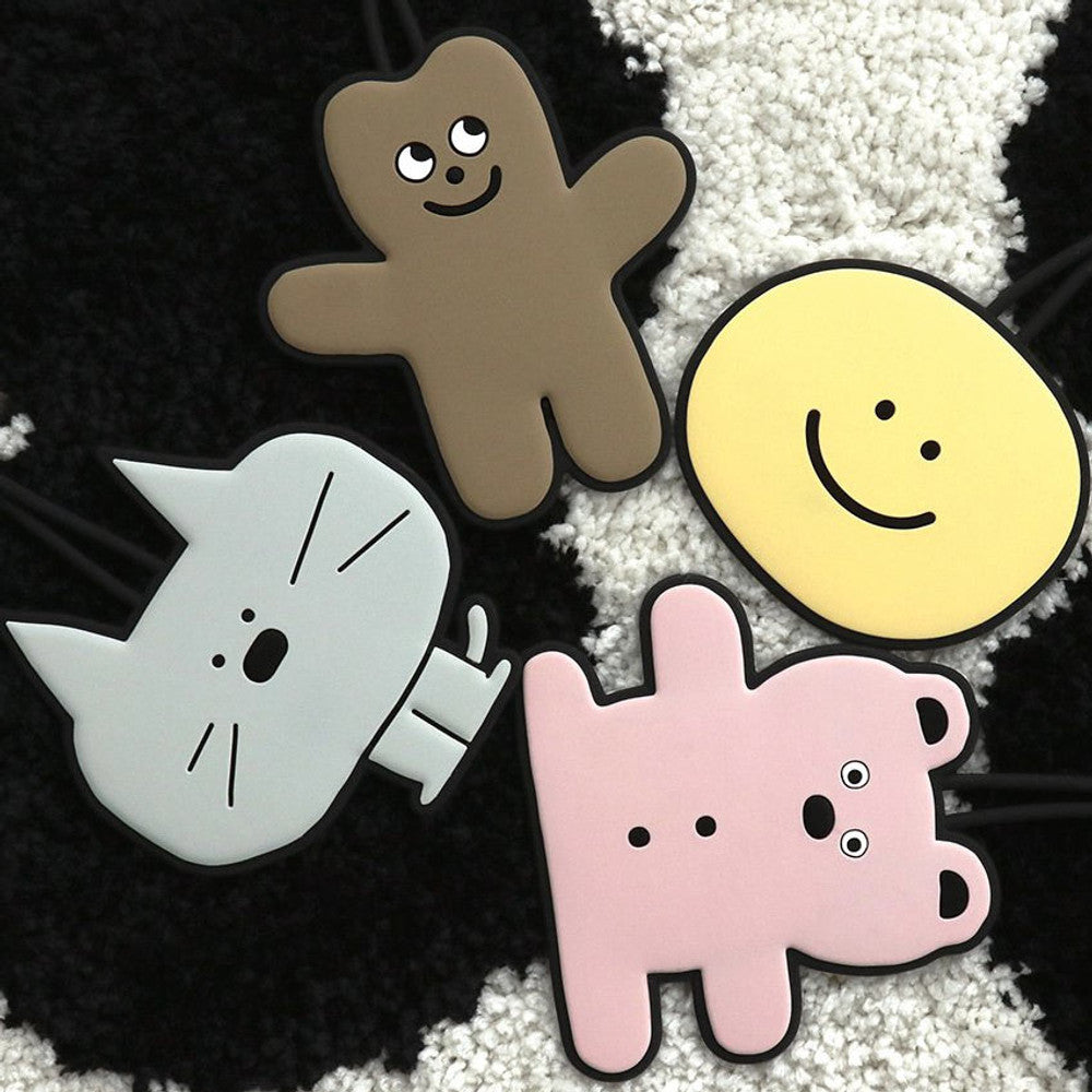 The Journal Shop - Close-up of brown bear, yellow smiley face, and pink bunny Doodle Luggage Tags on a dark surface.