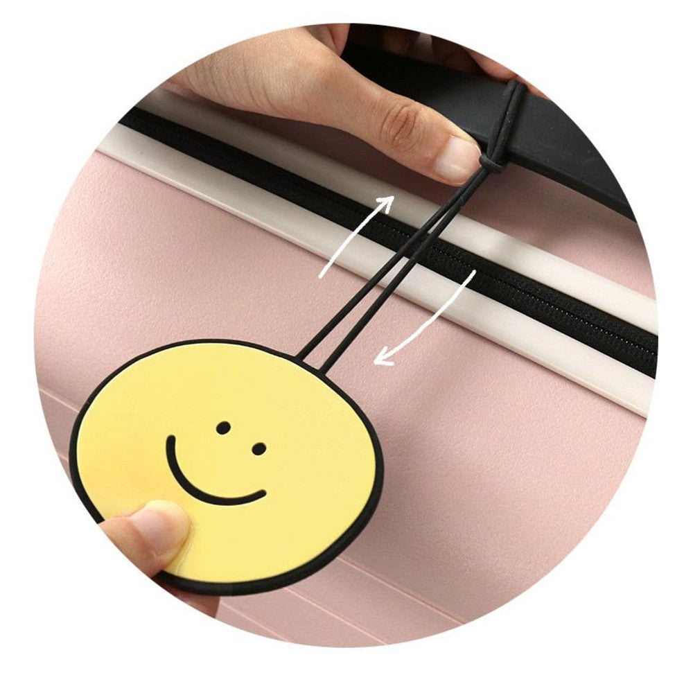 The Journal Shop - Yellow smiley Iconic Doodle Luggage Tag hanging from a pink suitcase.