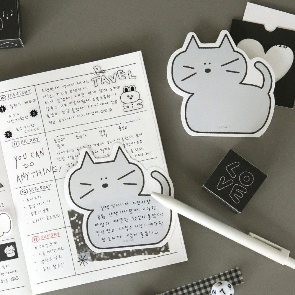 The Journal Shop - Grey cat-shaped Iconic Doodle Memo Pad used as a tear-off note inside an open planner with pen and stationery on desk.