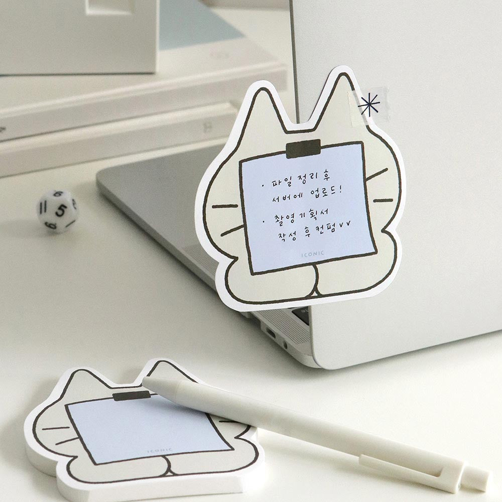 The Journal Shop - Grey cat-shaped Iconic Doodle Memo Pad “Message” design with blue note stuck on laptop and extra pad with pen on desk.