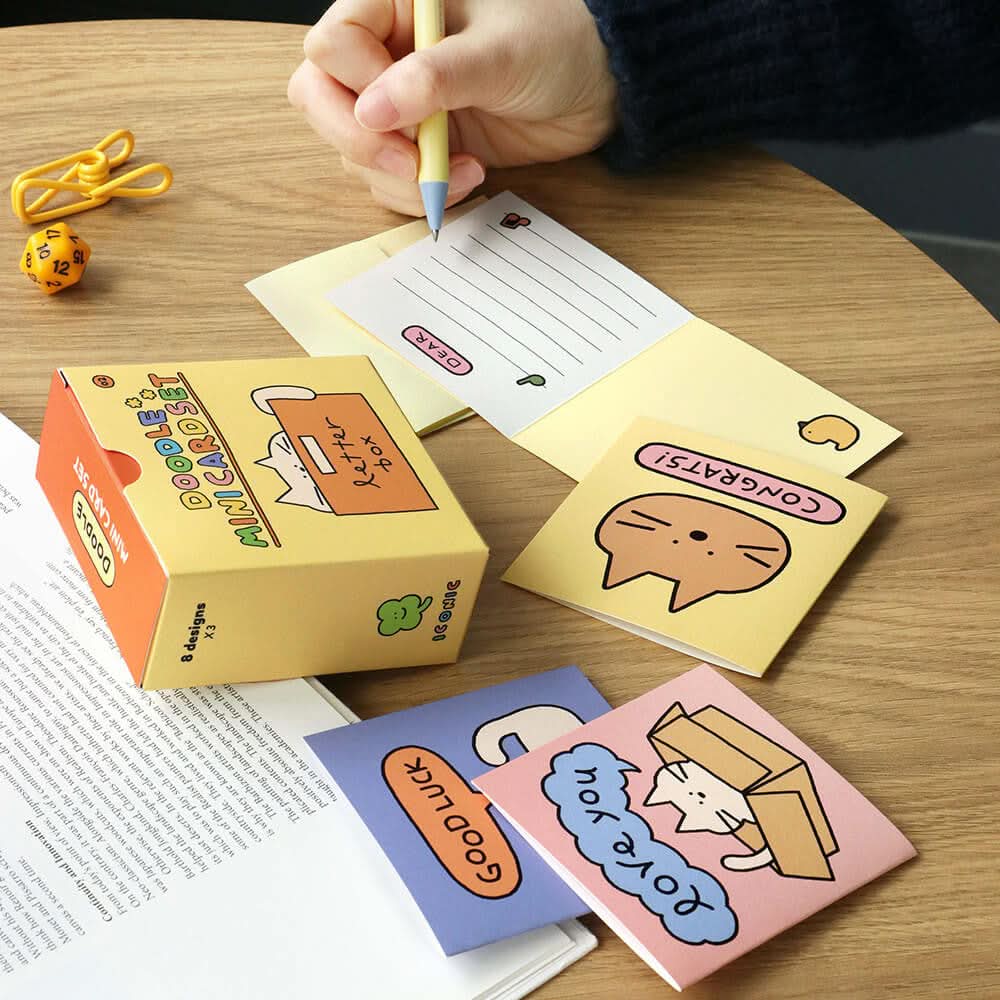 The Journal Shop - Person opening Iconic Doodle Mini Card Set yellow box and preparing to write on small doodle card.