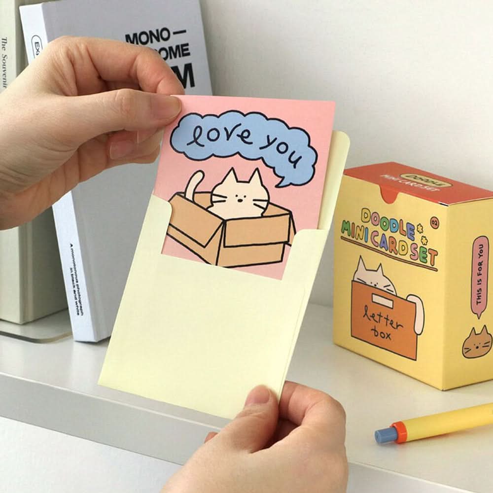 The Journal Shop - Person holding Iconic Doodle Mini Card with cheerful cat design and “love you” message.