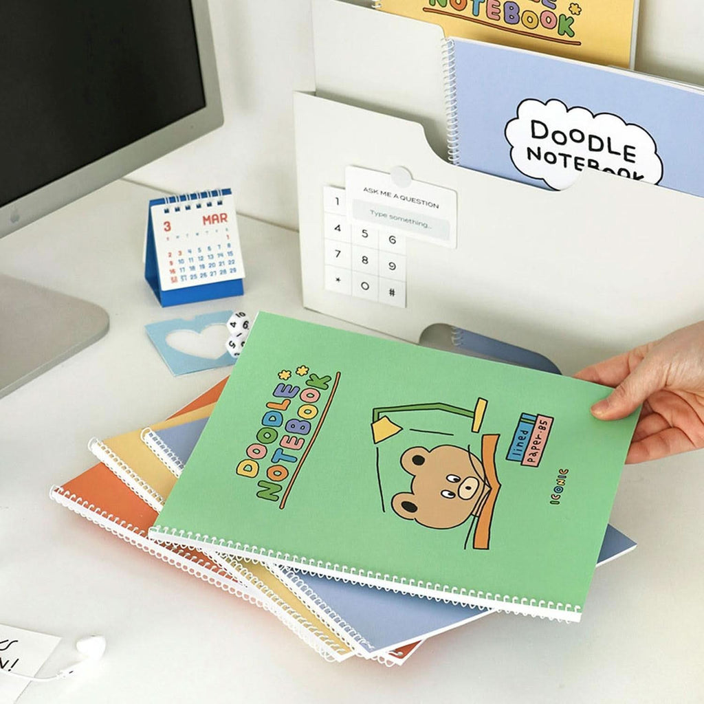 The Journal Shop - Iconic Doodle B5 Spiral Lined Notebook in green cover open flat on desk with writing inside.