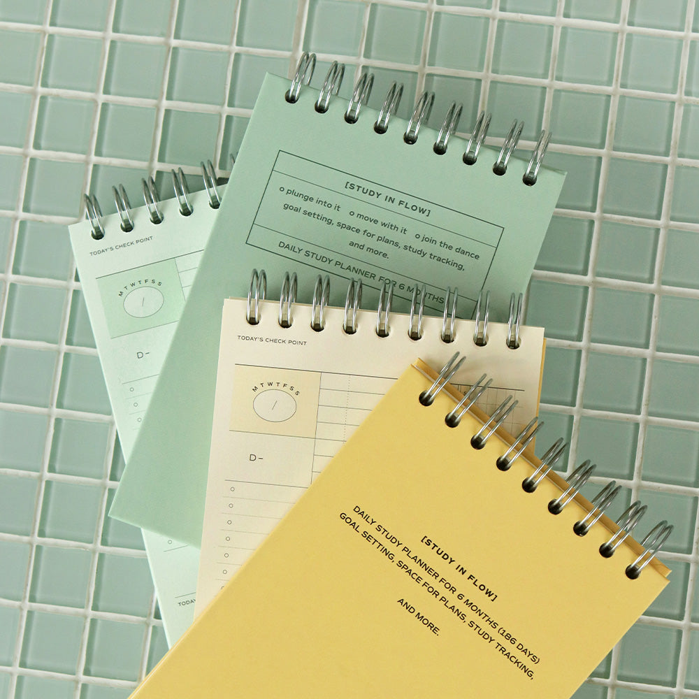 The Journal Shop - Iconic Flow B6 Spiral Study Planners in butter yellow and vintage green shown on tiled background with study accessories.