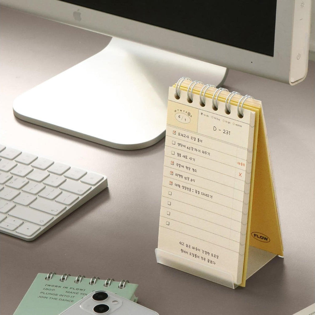 The Journal Shop - The yellow Iconic Flow Checklist displayed upright beside a keyboard and lamp, ready for daily use.