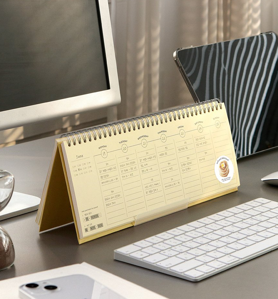 The Journal Shop - Yellow Iconic Flow Weekly Planner standing upright beside a tablet and keyboard.