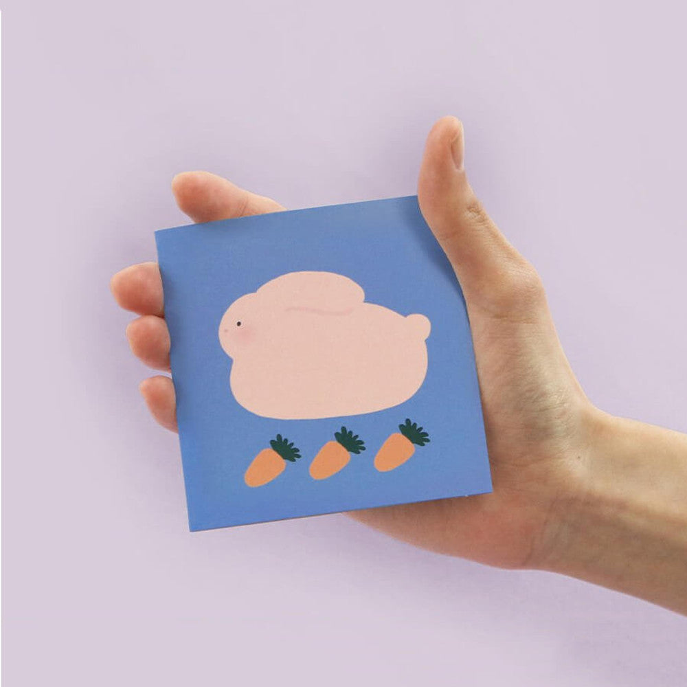 The Journal Shop - Person holding Iconic Happy Mini Card with animals' illustration on pastel purple background.
