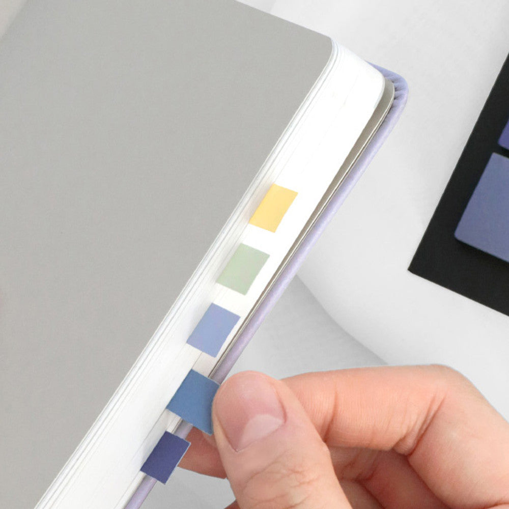 The Journal Shop - Hand placing pastel sticky notes into a notebook for organisation and colour coding.