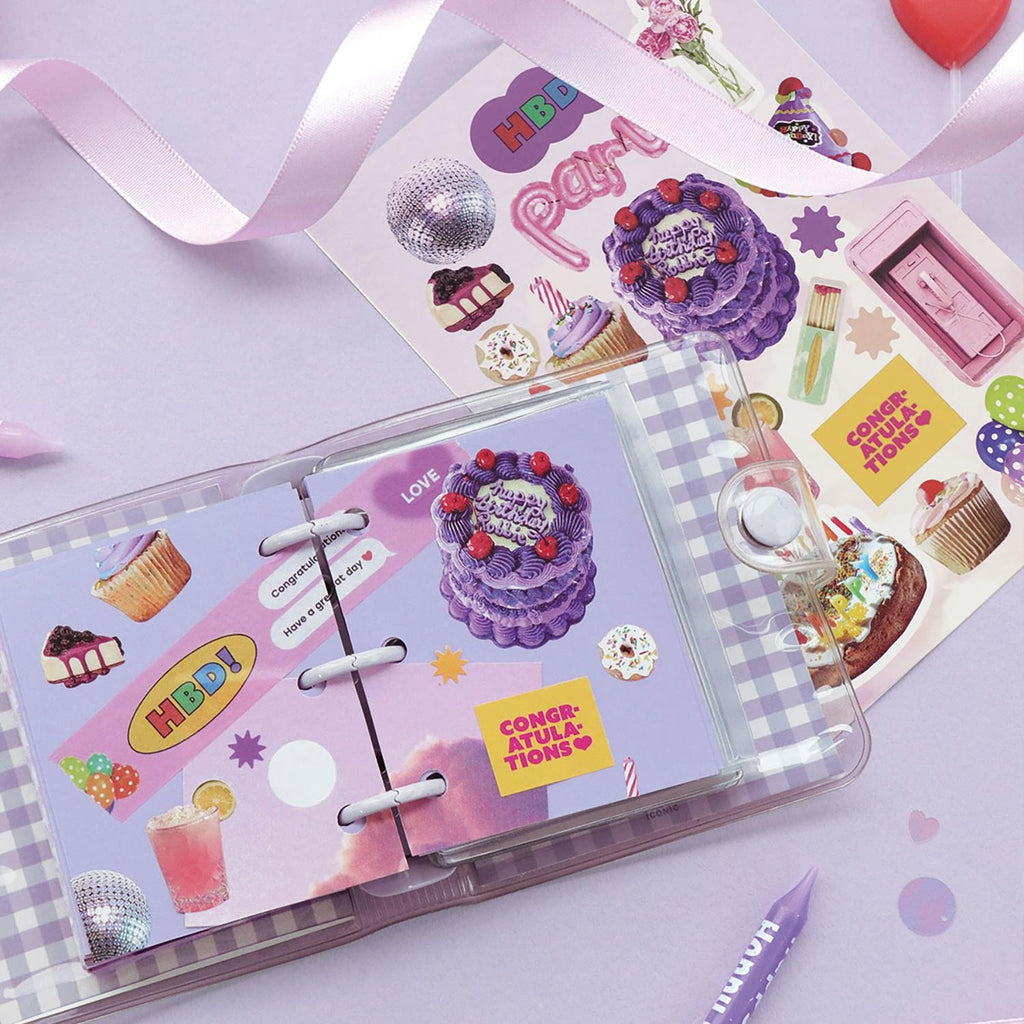 The Journal Shop - A close-up of an open scrapbook decorated with colourful stickers from the Iconic Just Object Sticker Pack, featuring cakes, drinks, and celebration motifs on a pastel purple background.