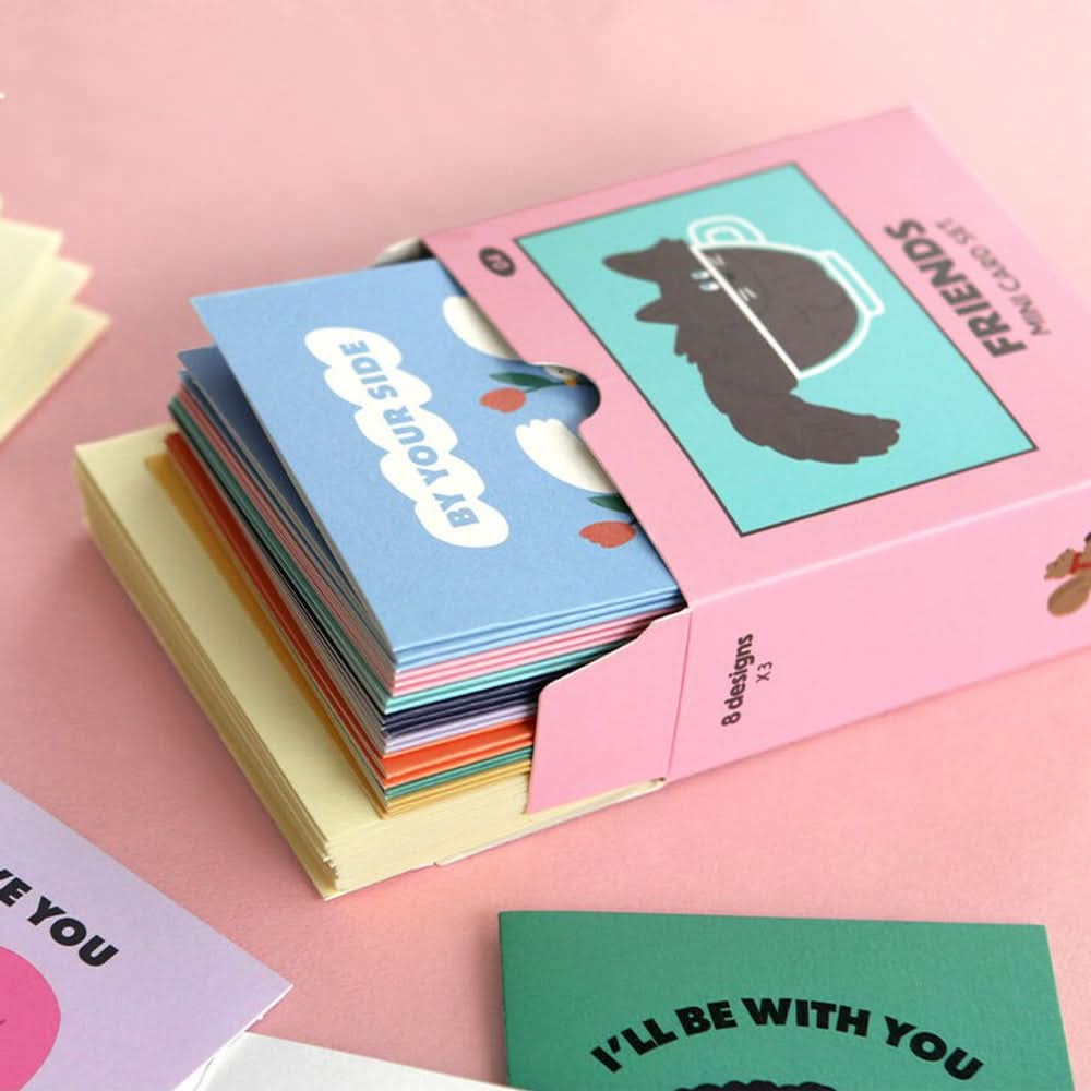 The Journal Shop - Open Iconic Mini Friends Card Set box showing stacked cards in various playful designs on pink surface.