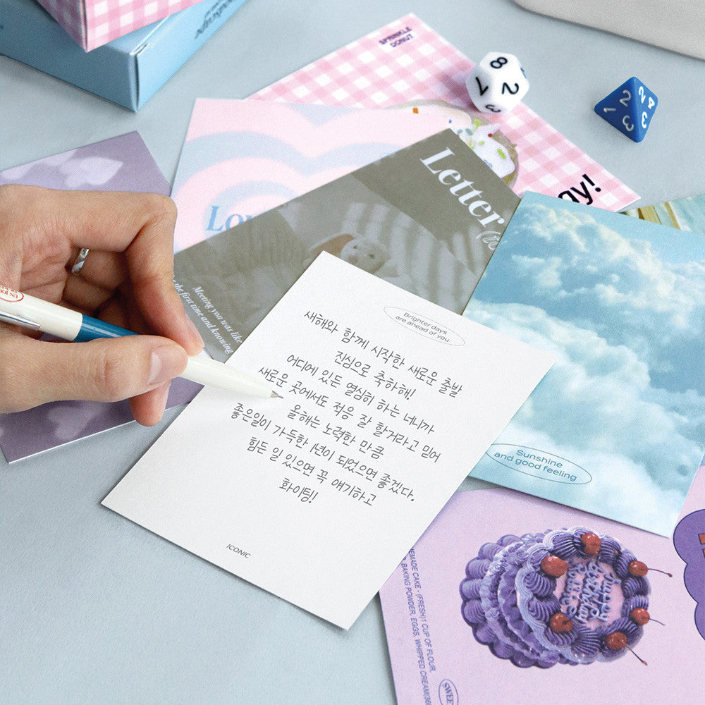 The Journal Shop - Person writing on Iconic Moodscape Message Card with blue envelope and stationery beside.