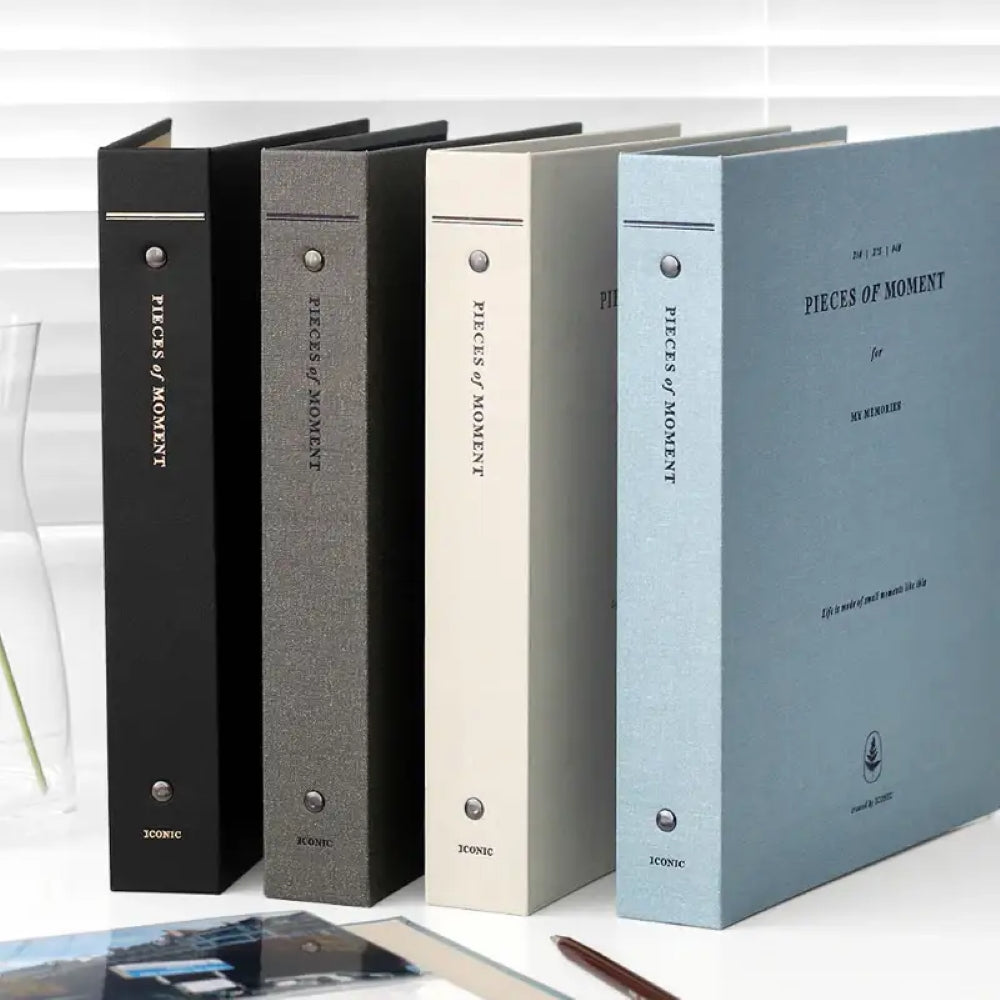 The Journal Shop - Collection of Iconic Pieces of Moment Memory Binders in assorted colours including black, khaki, light gray, and blue, arranged on a desk.